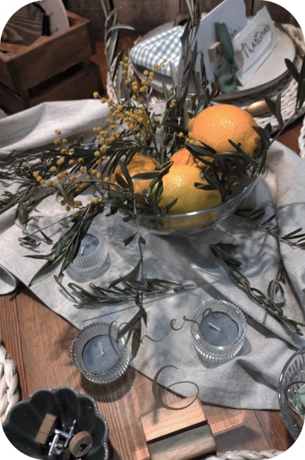 Centro de mesa con limones y olivo sobre una mesa decorada con velas
