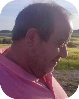 Hombre posando en el campo con camisa rosa